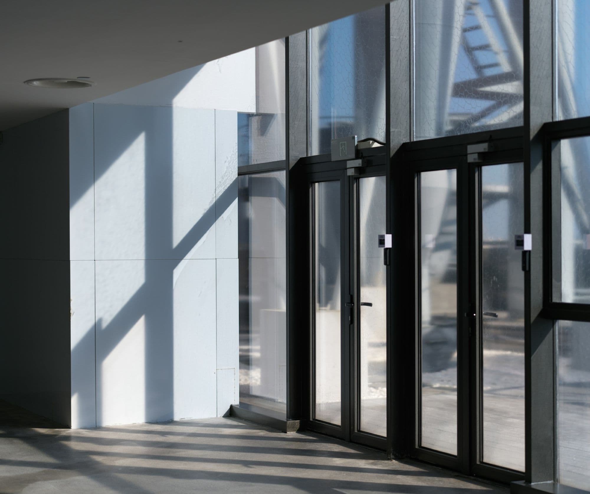 Black-framed glass entrance doors in a sunlit lobby