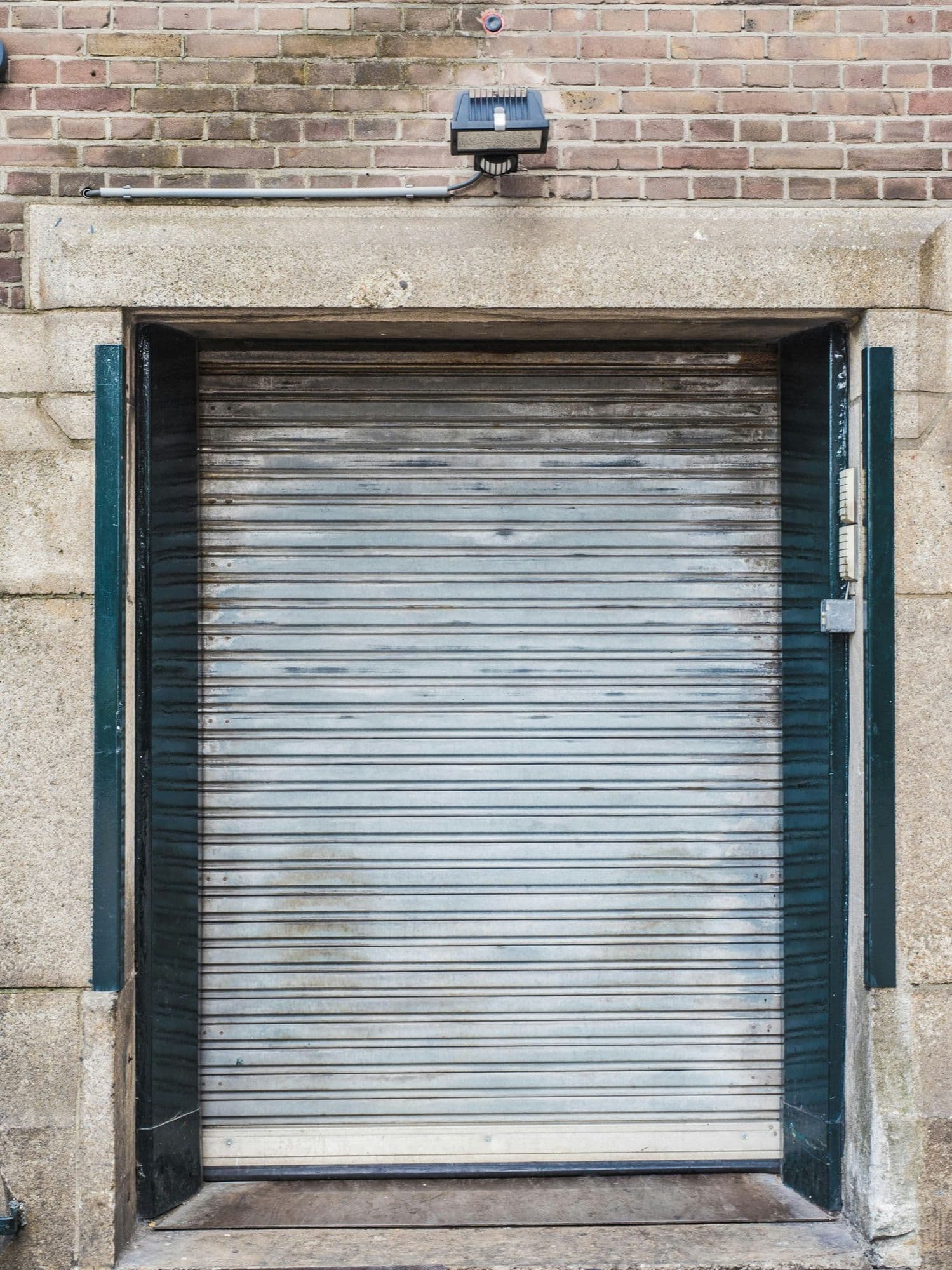 A steel roller shutter closed within a stone doorway