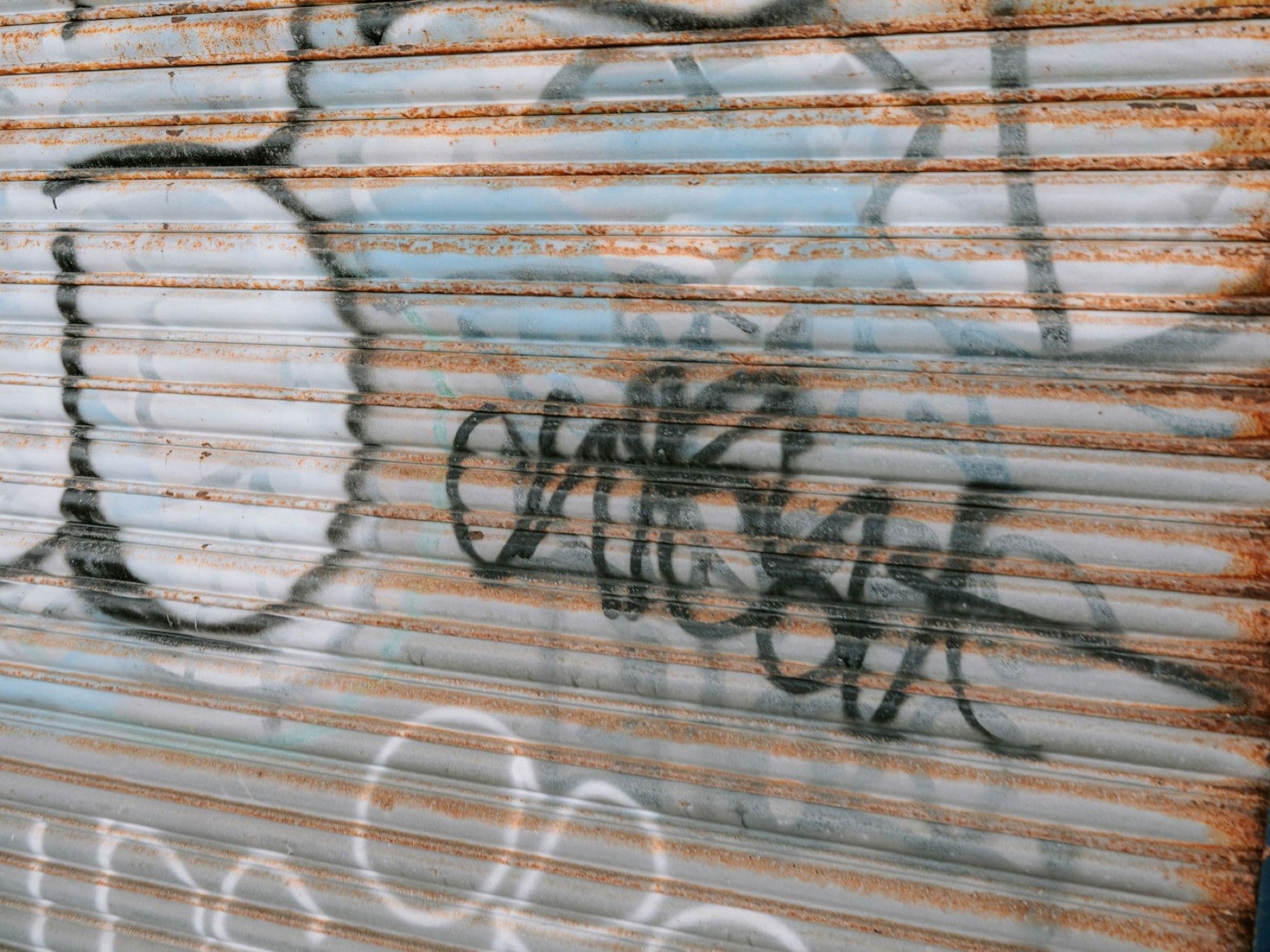 A rusted roller shutter covered in graffiti